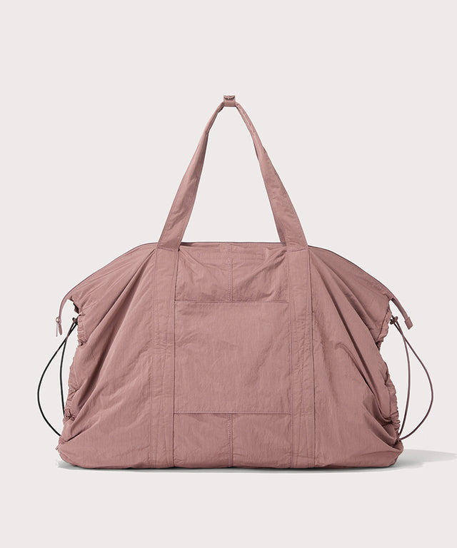 A dusty rose pink lightweight nylon duffel bag with dual top handles, shown against a solid light gray background.