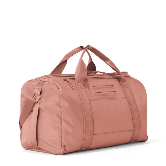 3/4 back view of Monaco garment duffle in warm dust showing back zippered tech pocket and phone/passport pockets