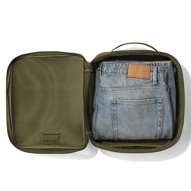 Large Roma packing cube in dark moss open with jeans inside.