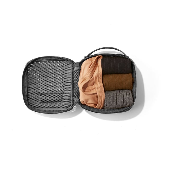 Small Roma packing cube in carbon blackt open with socks and a tank top inside.