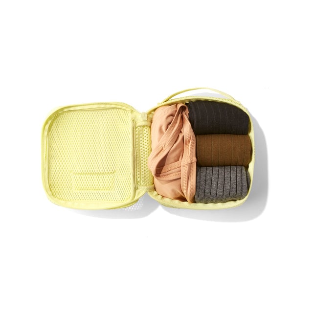 Small Roma packing cube in citrine yellowt open with socks and a tank top inside.