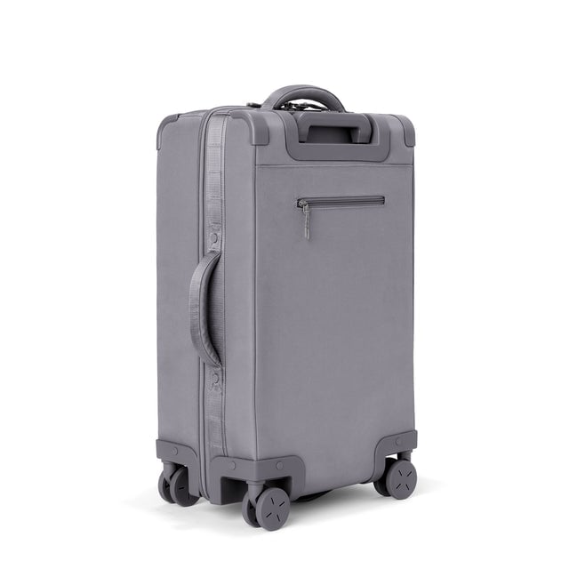 3/4 back view of Seattle carry-on rolling luggage 23.5” in ash showing side handle and back zippered phone/passport pocket