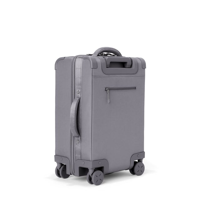 3/4 back view of Seattle carry-on rolling luggage 20.5” in ash showing side handle and back zippered phone/passport pocket