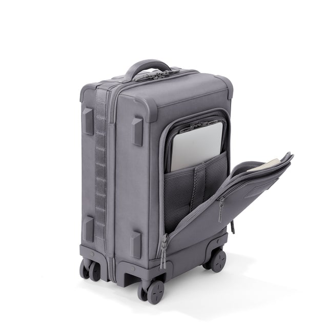 ¾ front view of Seattle carry-on rolling luggage 20.5” in ash with front flap opened. Caption: Interior slip pocket fits most 13