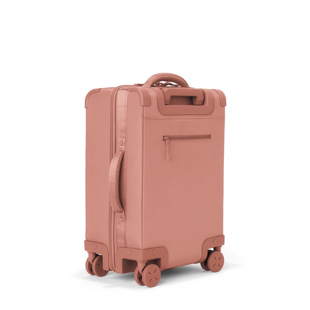 3/4 back view of Seattle carry-on rolling luggage 20.5” in warm dust showing side handle and back zippered phone/passport pocket