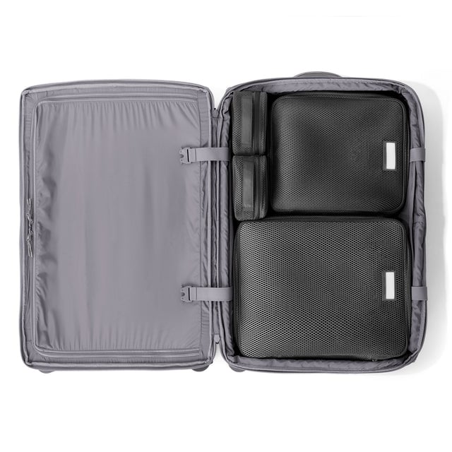 Top down of Sydney checked rolling luggage 28.5” in ash grey with interior divider zipped and packing cubes packed into the right side. hover