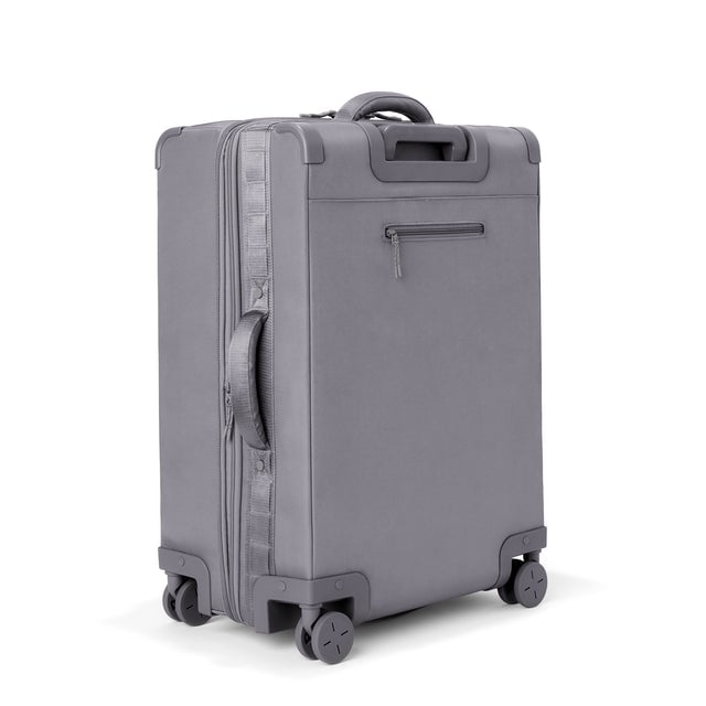 3/4 back view of Sydney checked rolling luggage 25” in ash grey showing side handle and back zippered phone/passport pocket
