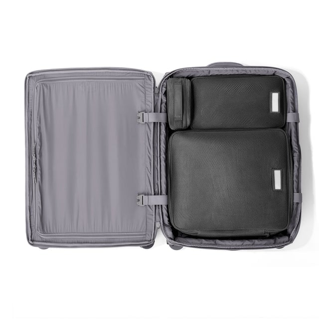 Top down of Sydney checked rolling luggage 25” in ash grey with interior divider zipped and packing cubes packed into the right side. hover