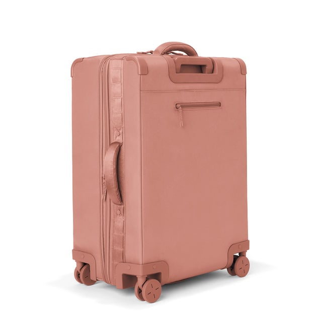 3/4 back view of Sydney checked rolling luggage 25” in warm dust showing side handle and back zippered phone/passport pocket