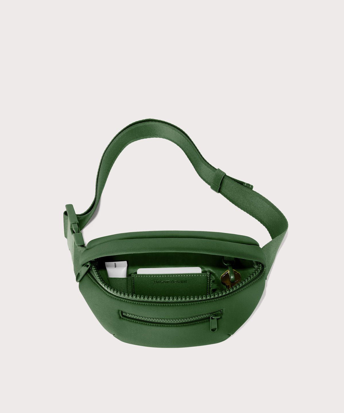Dagne Dover Ace Fanny Pack in  a rich, classic forest green  unzipped, exposing the interior pockets
