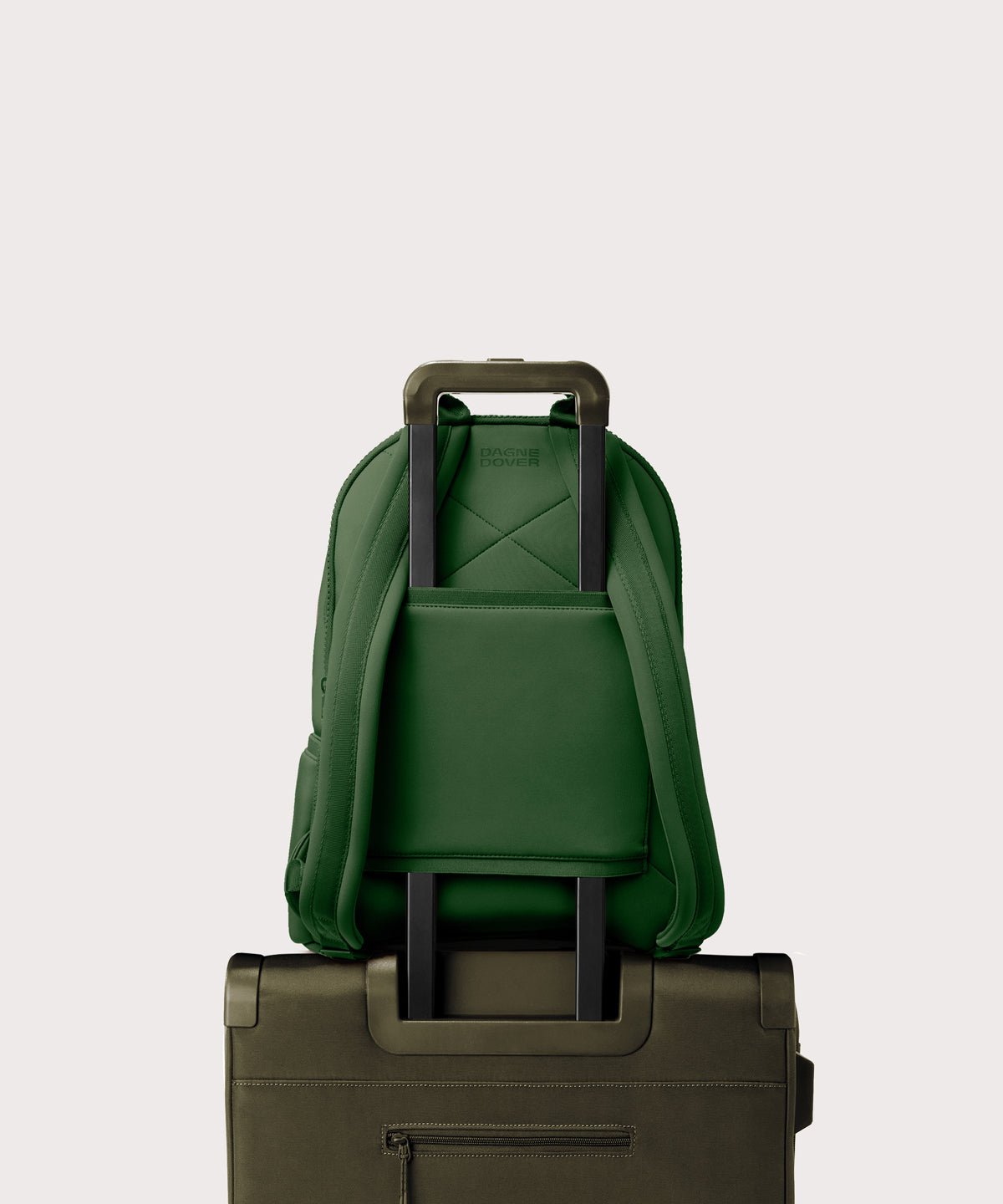 Dagne Dover large Dakota Neoprene Backpack in a rich, classic forest green strapped to luggage with the neoprene luggage-handle sleeve.
