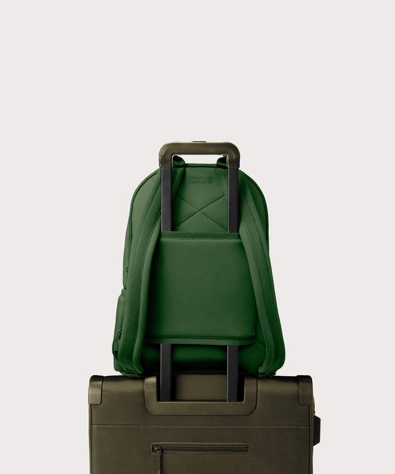 Dagne Dover large Dakota Neoprene Backpack in a rich, classic forest green strapped to luggage with the neoprene luggage-handle sleeve.
