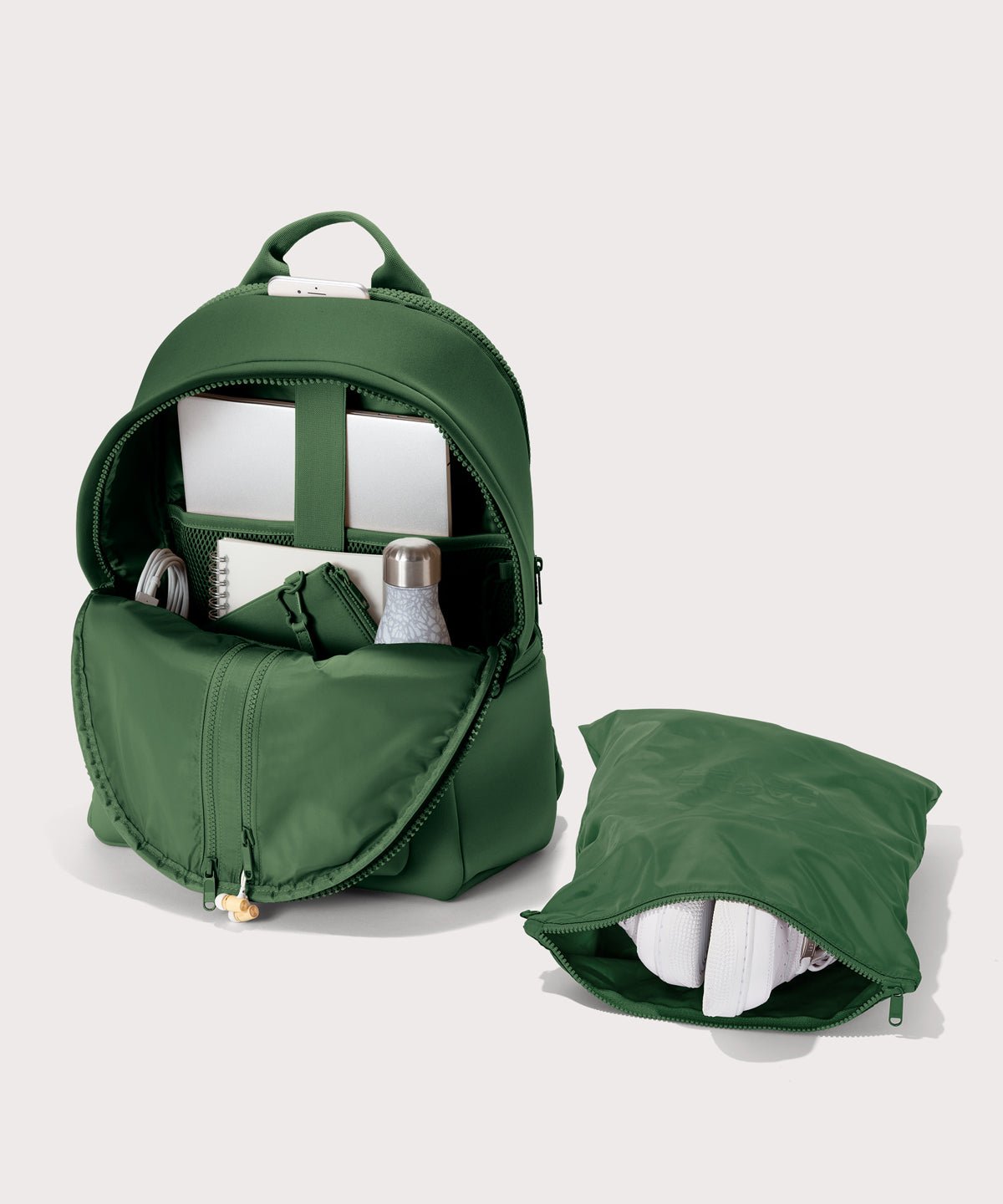 Dagne Dover large Dakota Neoprene Backpack in a rich, classic forest green unzipped, showing the interior pockets and shoe bag.
