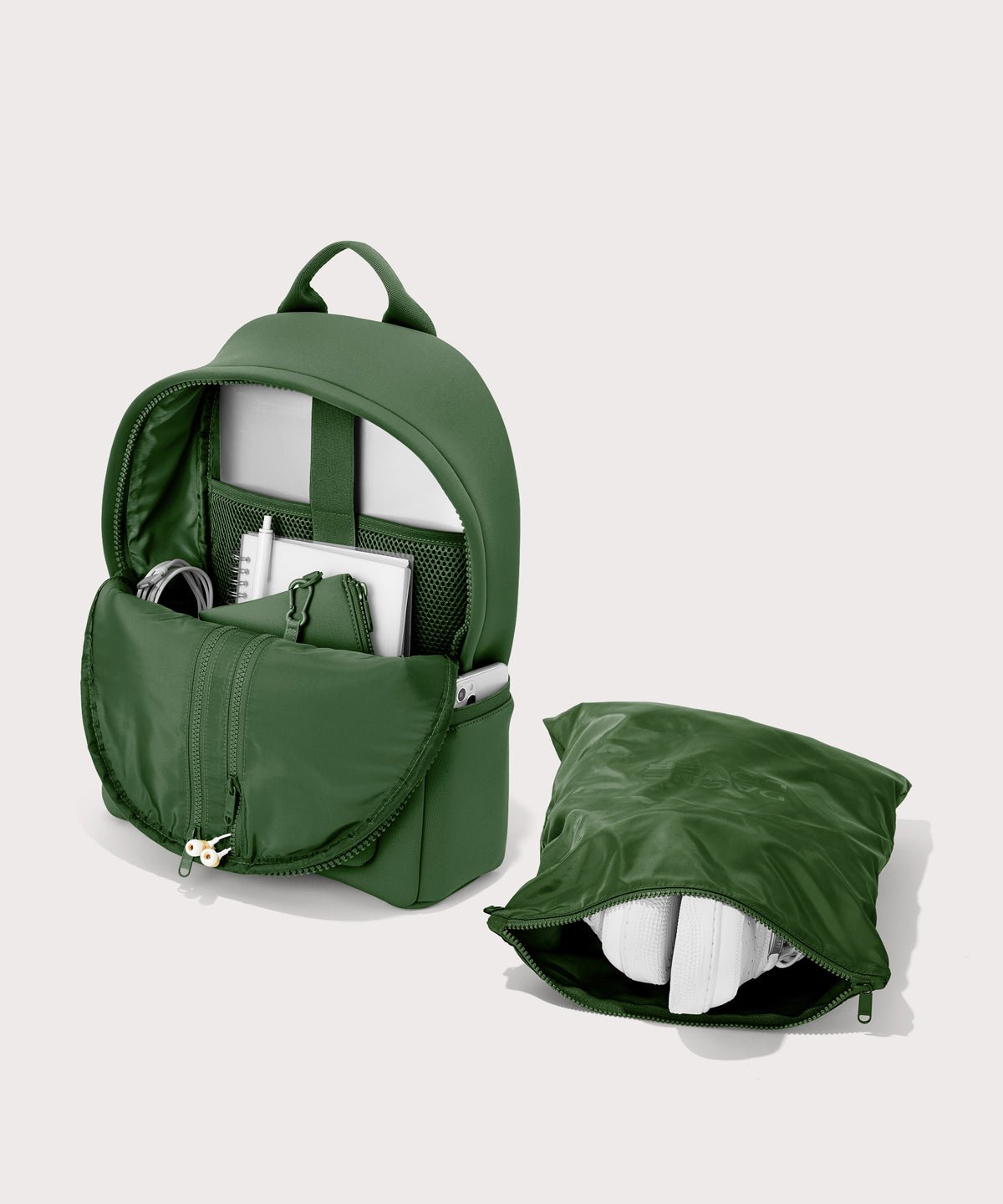 Dagne Dover medium Dakota Neoprene Backpack in a rich, classic forest green unzipped, showing the interior pockets and shoe bag.
