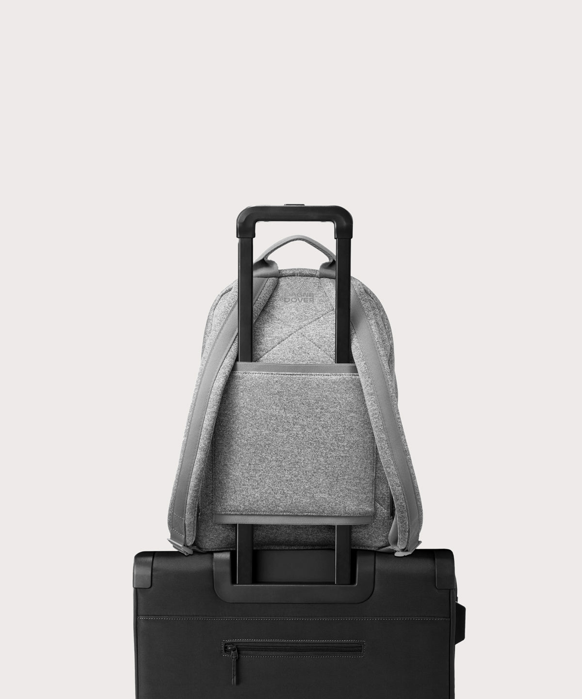 Dagne Dover medium Dakota Neoprene Backpack in grey strapped to luggage with the neoprene luggage-handle sleeve.
