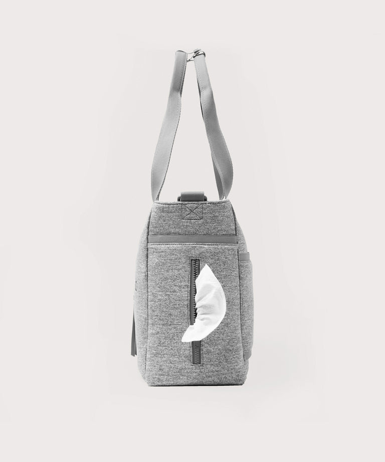 Dagne Dover large Wade Diaper Tote in grey seen from the side, with a wet wipe poking out of the slip pocket.
