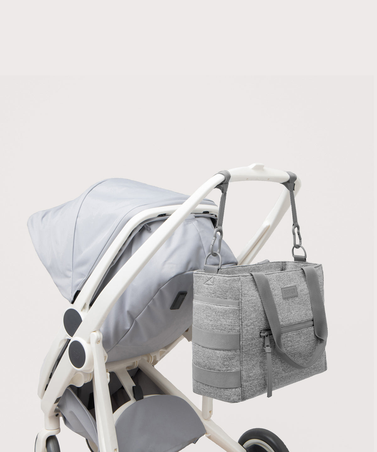 Dagne Dover large Wade Diaper Tote in grey strapped to the handle of a stroller.
