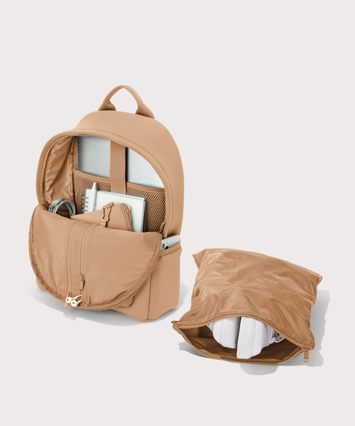 Dagne Dover medium Dakota Neoprene Backpack in camel brown unzipped, showing the interior pockets and shoe bag.
