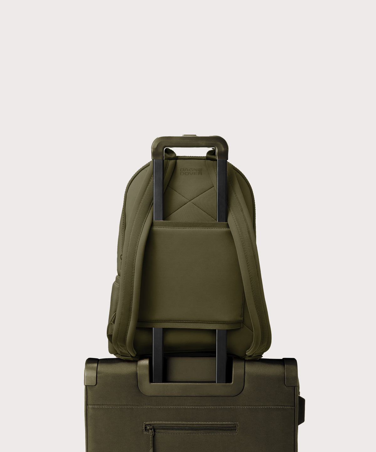 Dagne Dover large Dakota Neoprene Backpack in dark moss strapped to luggage with the neoprene luggage-handle sleeve.
