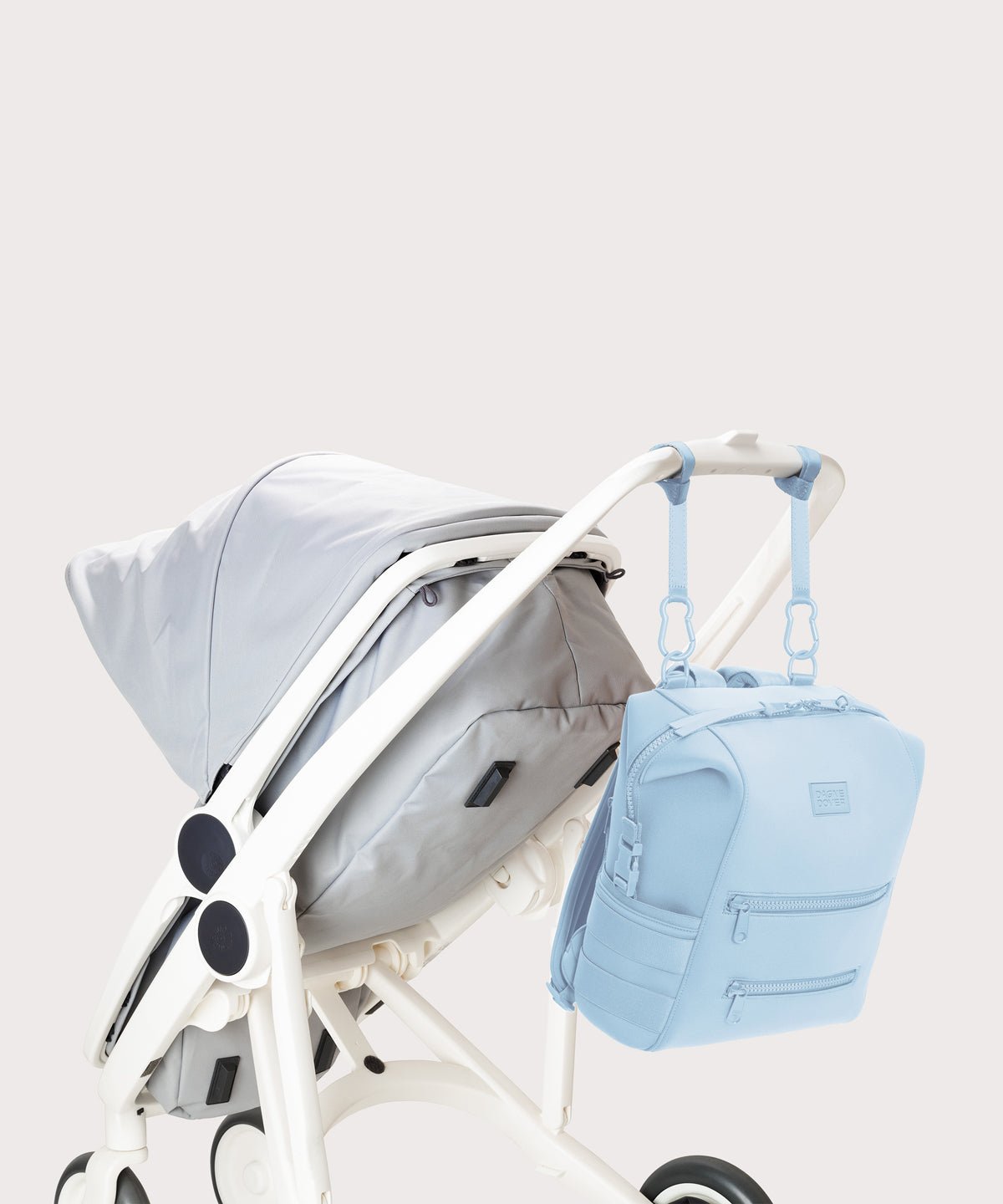 Dagne Dover Medium Indi Diaper Backpack in an airy, lighter sky blue. attached to a stroller.
