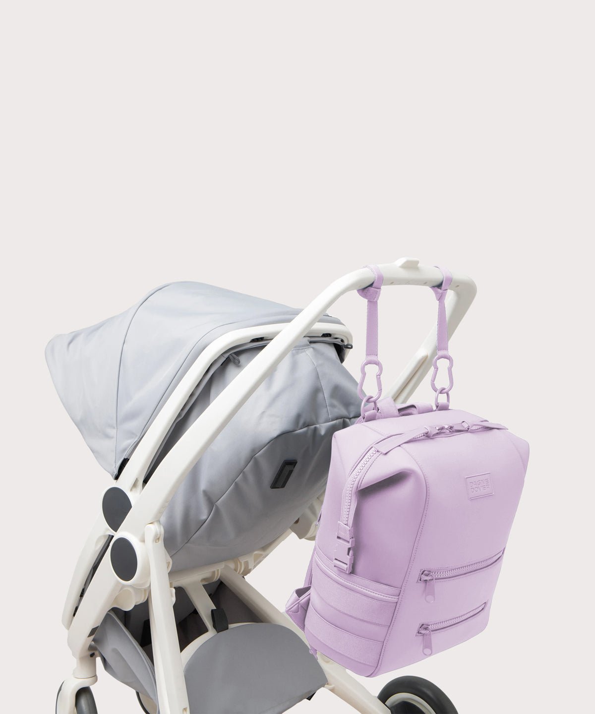 Dagne Dover Large Indi Diaper Backpack in a soft purple with grey undertones attached to a stroller.
