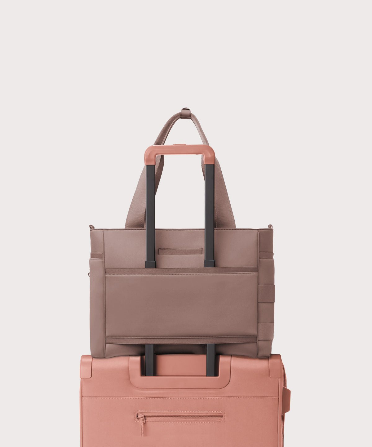 Dagne Dover large Wade Diaper Tote in pink with the neoprene luggage sleeve attached to a suitcase handle.
