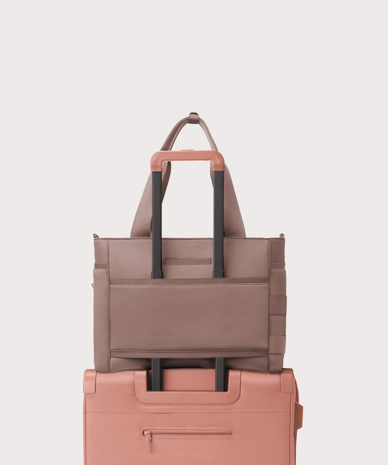 Dagne Dover large Wade Diaper Tote in pink with the neoprene luggage sleeve attached to a suitcase handle.
