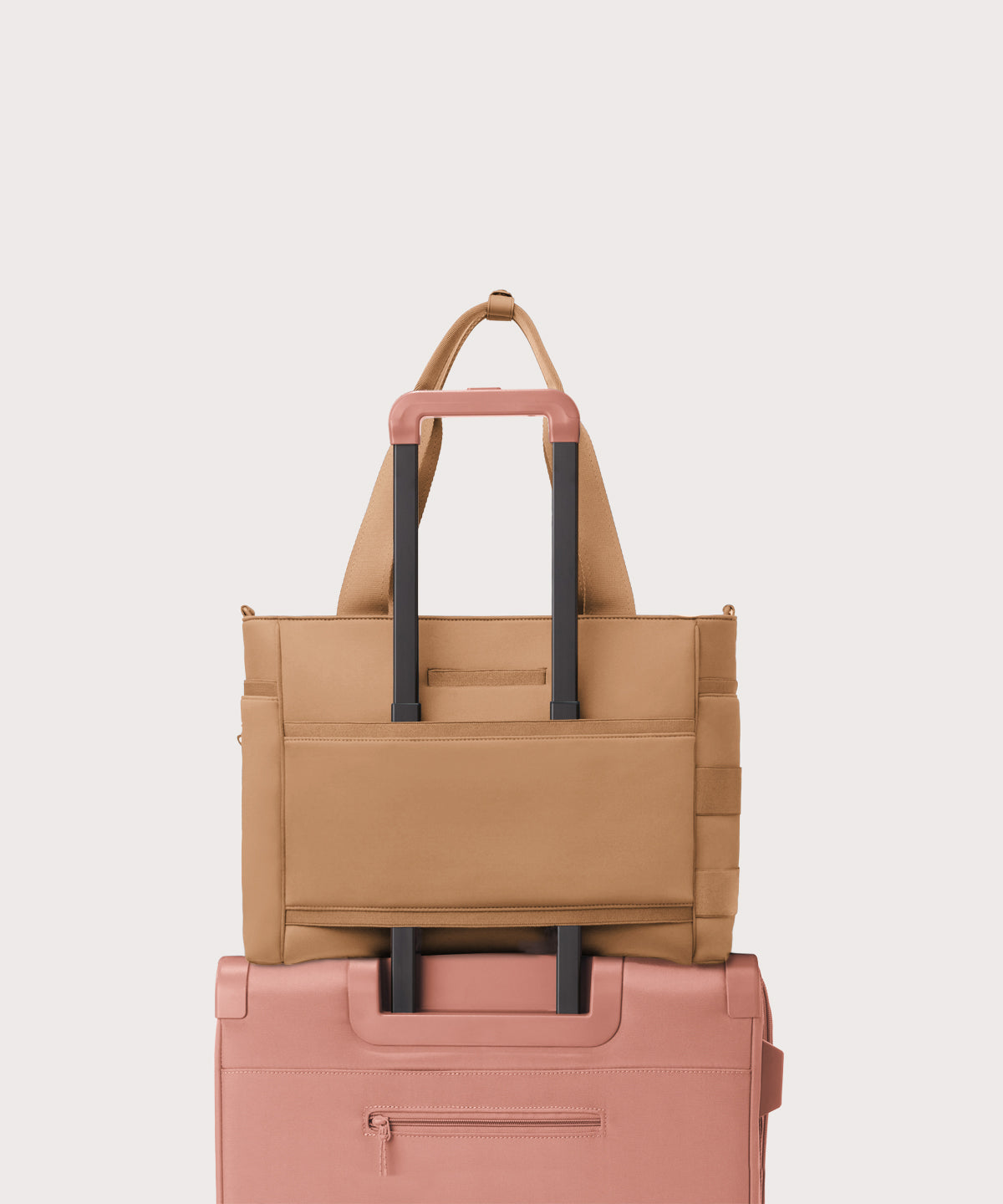 Dagne Dover large Wade Diaper Tote in camel brown with the neoprene luggage sleeve attached to a suitcase handle.
