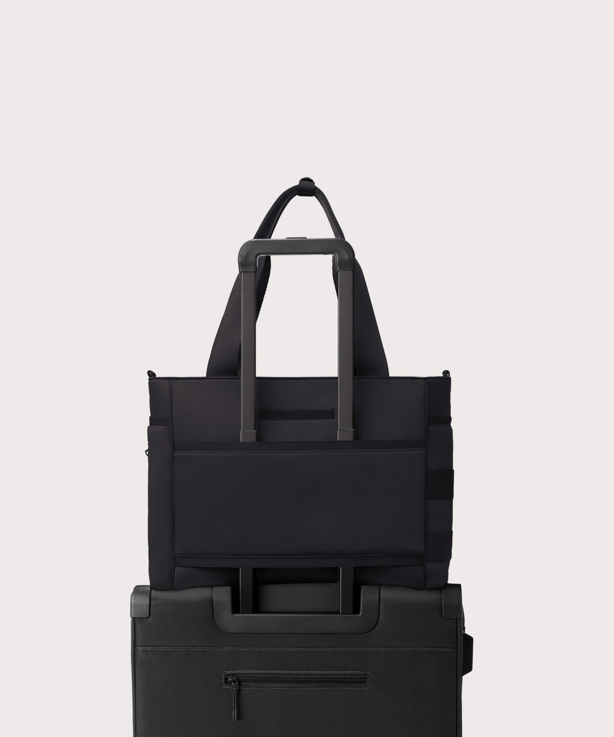 Dagne Dover large Wade Diaper Tote in black with the neoprene luggage sleeve attached to a suitcase handle.
