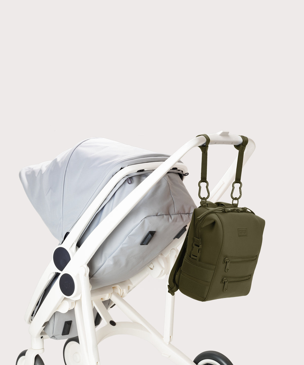 Dagne Dover small Indi Diaper Backpack in dark moss attached to a stroller.
