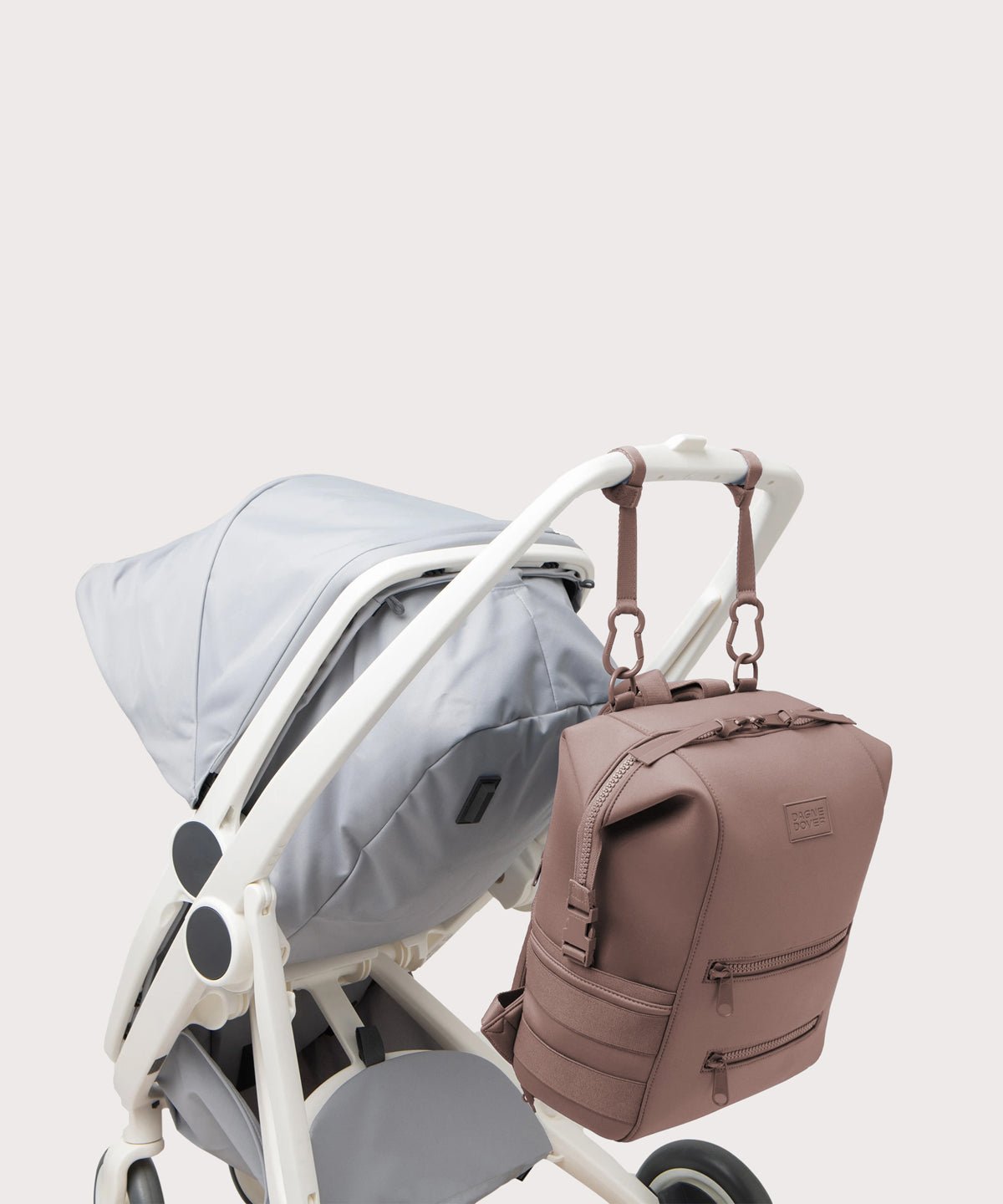 Dagne Dover Large Indi Diaper Backpack in pink attached to a stroller.
