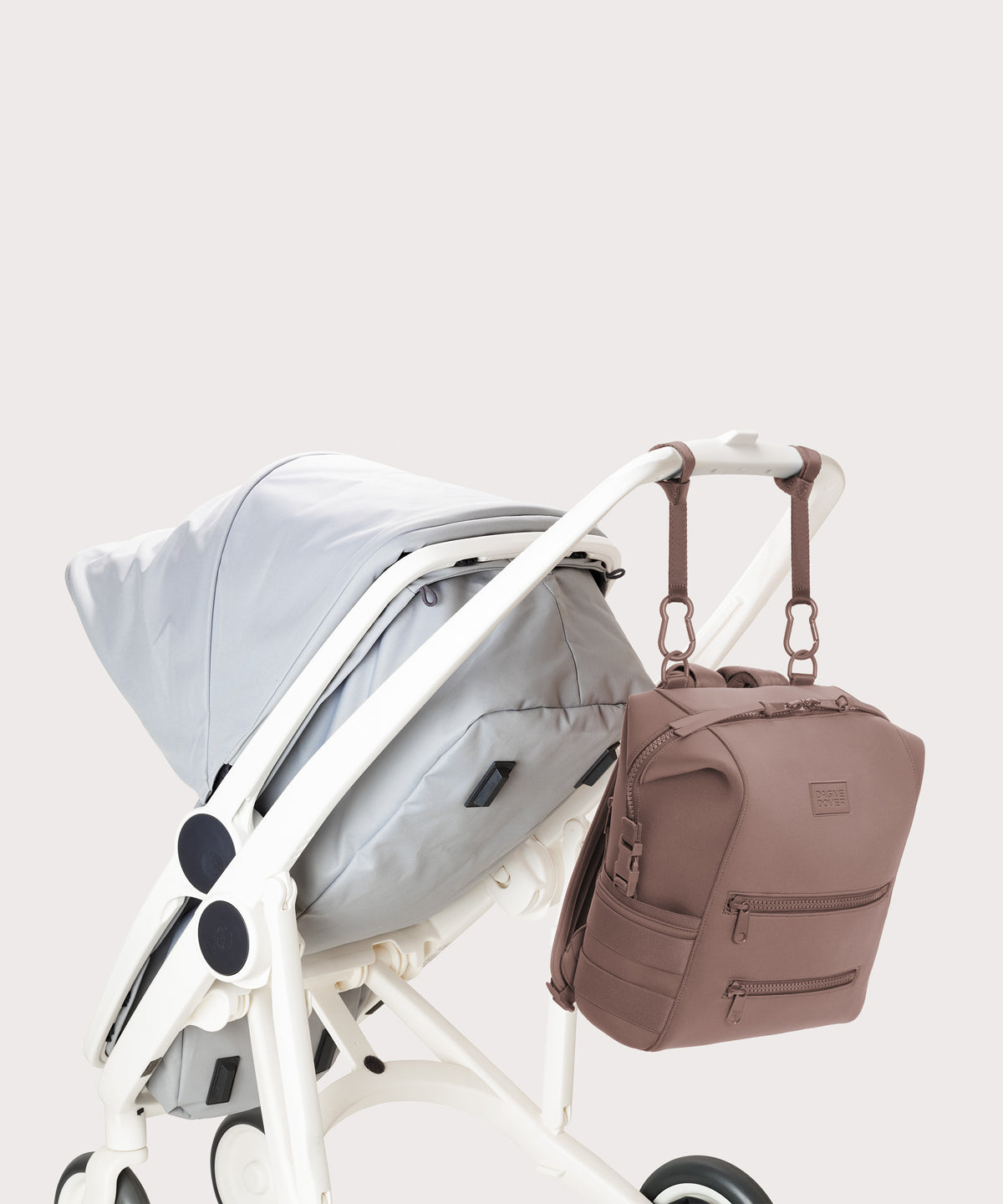 Dagne Dover medium Indi Diaper Backpack in pink attached to a stroller.
