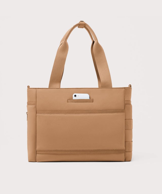 Dagne Dover large Wade Diaper Tote in camel brown seen from the back with a phone in the exterior phone pocket.
