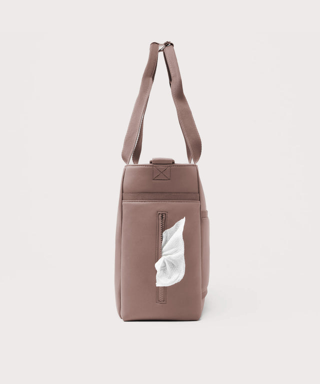Dagne Dover large Wade Diaper Tote in pink seen from the side, with a wet wipe poking out of the slip pocket.
