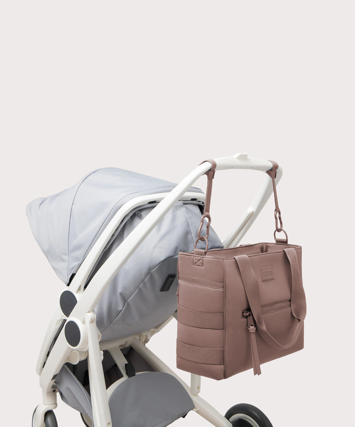 Dagne Dover large Wade Diaper Tote in pink strapped to the handle of a stroller.
