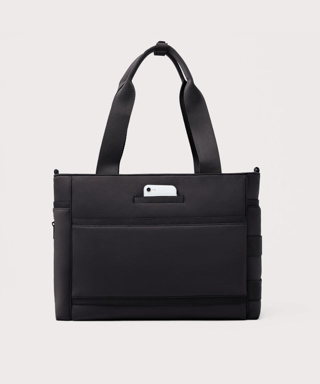 Dagne Dover large Wade Diaper Tote in black seen from the back with a phone in the exterior phone pocket.
