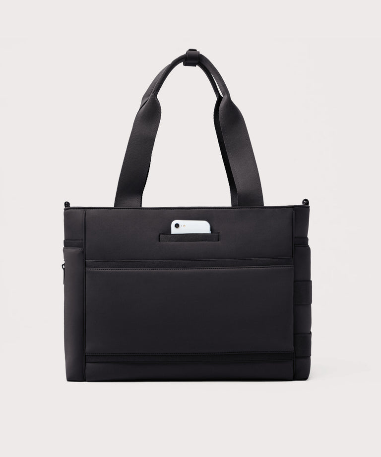 Dagne Dover large Wade Diaper Tote in black seen from the back with a phone in the exterior phone pocket.
