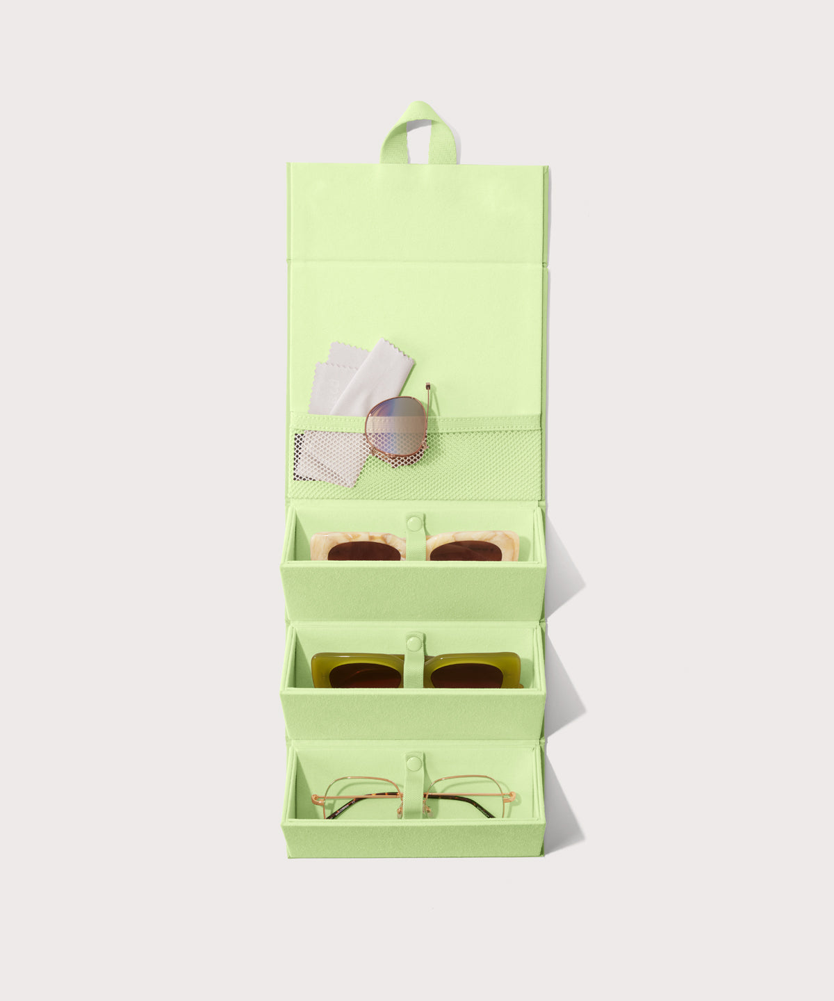 Dagne Dover Remi foldable glasses holder in matcha green hung up and holding glasses.
