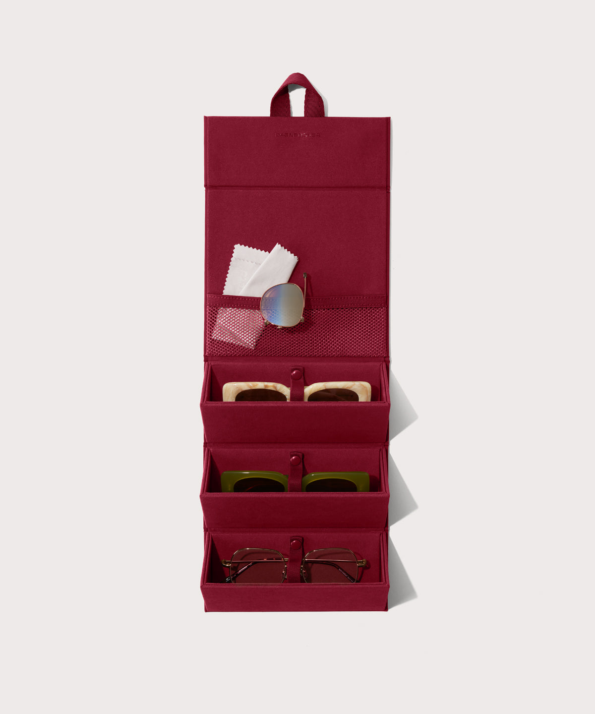 Dagne Dover Remi foldable glasses holder in spice red hung up and holding glasses.
