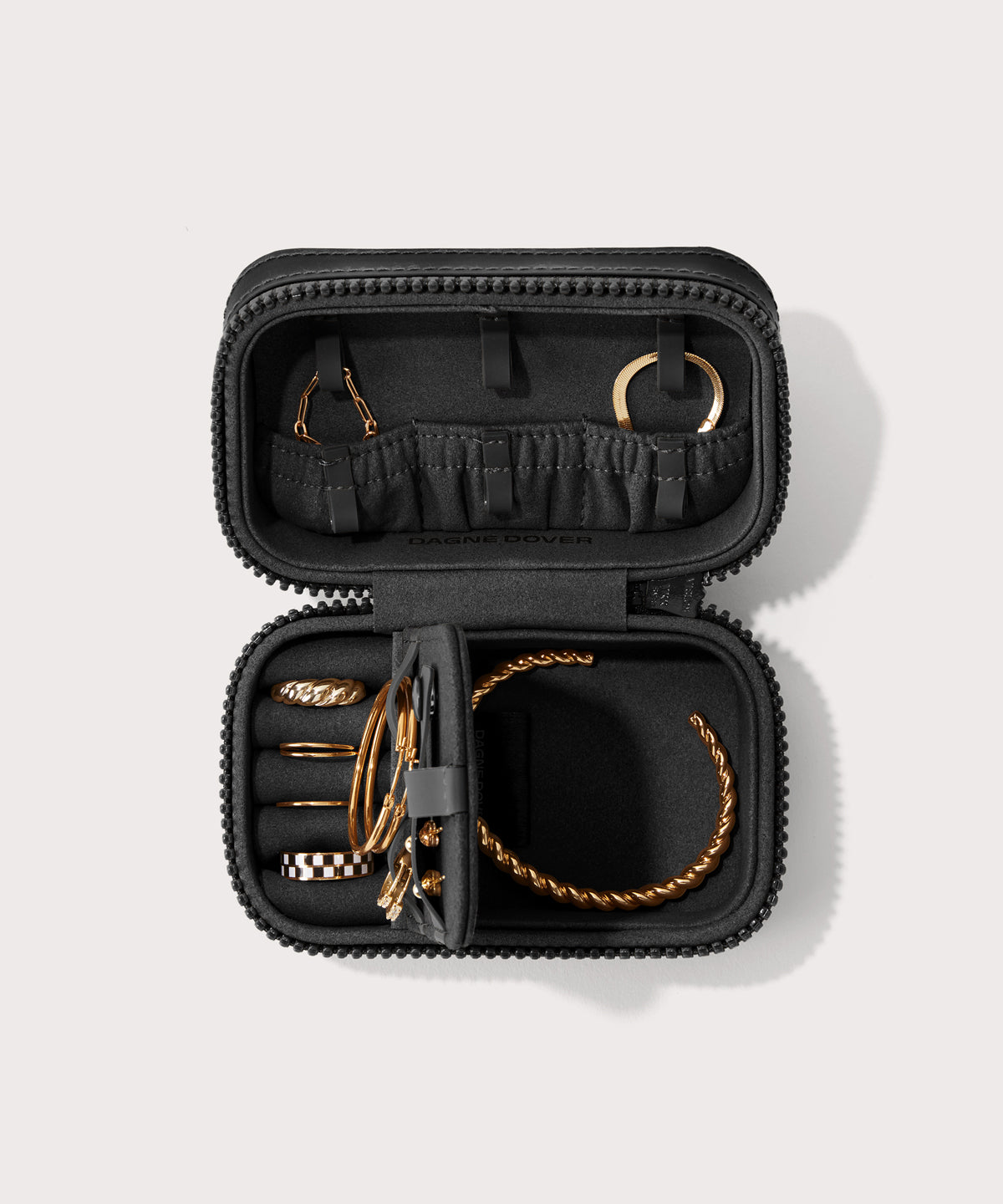 Dagne Dover small Frankie Jewelry Case in black, seen open from above with jewelry inside the interior compartment.