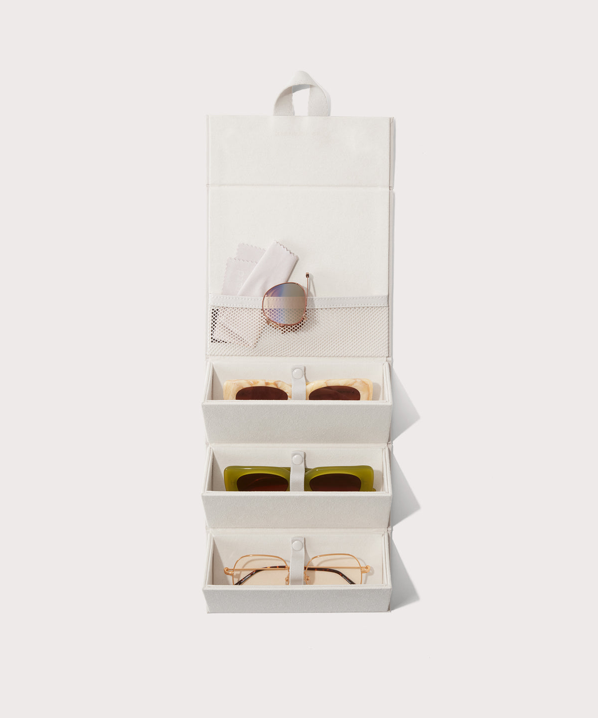 Dagne Dover Remi foldable glasses holder in white hung up and holding glasses.
