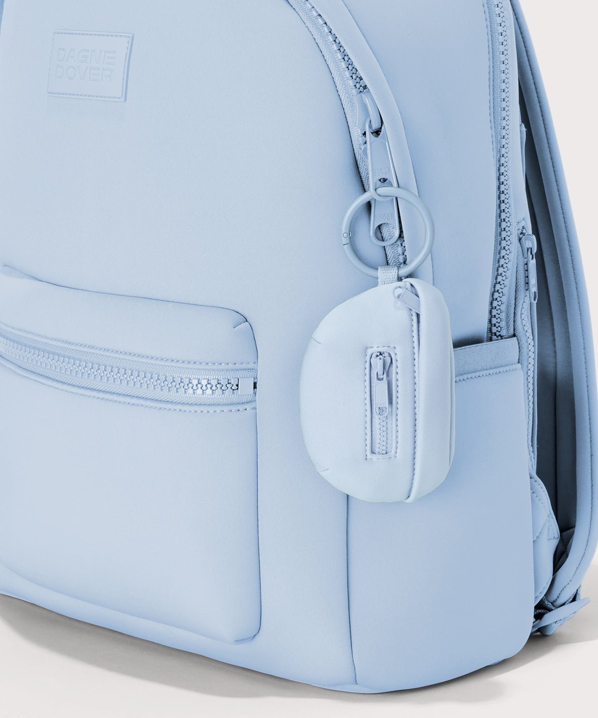 Dagne Dover Ace Keychain in an airy, lighter sky blue. clipped onto a backpack