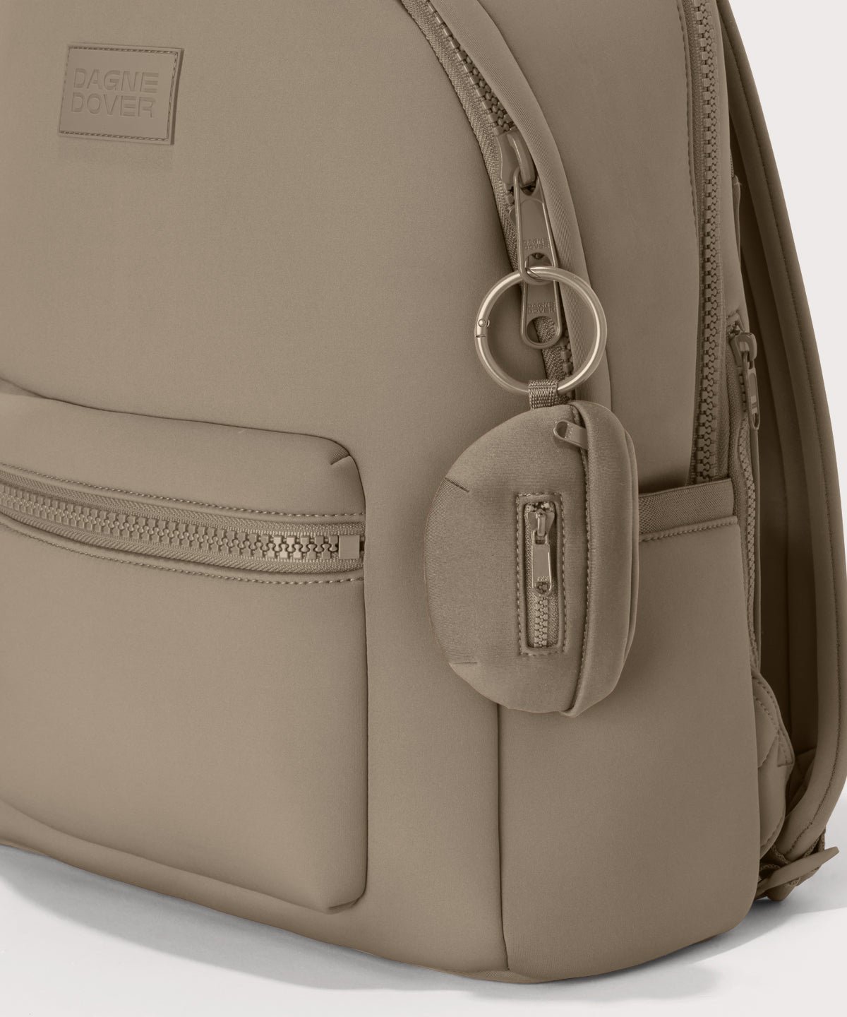 Dagne Dover Ace Keychain in a medium-dark, creamy tan clipped onto a backpack