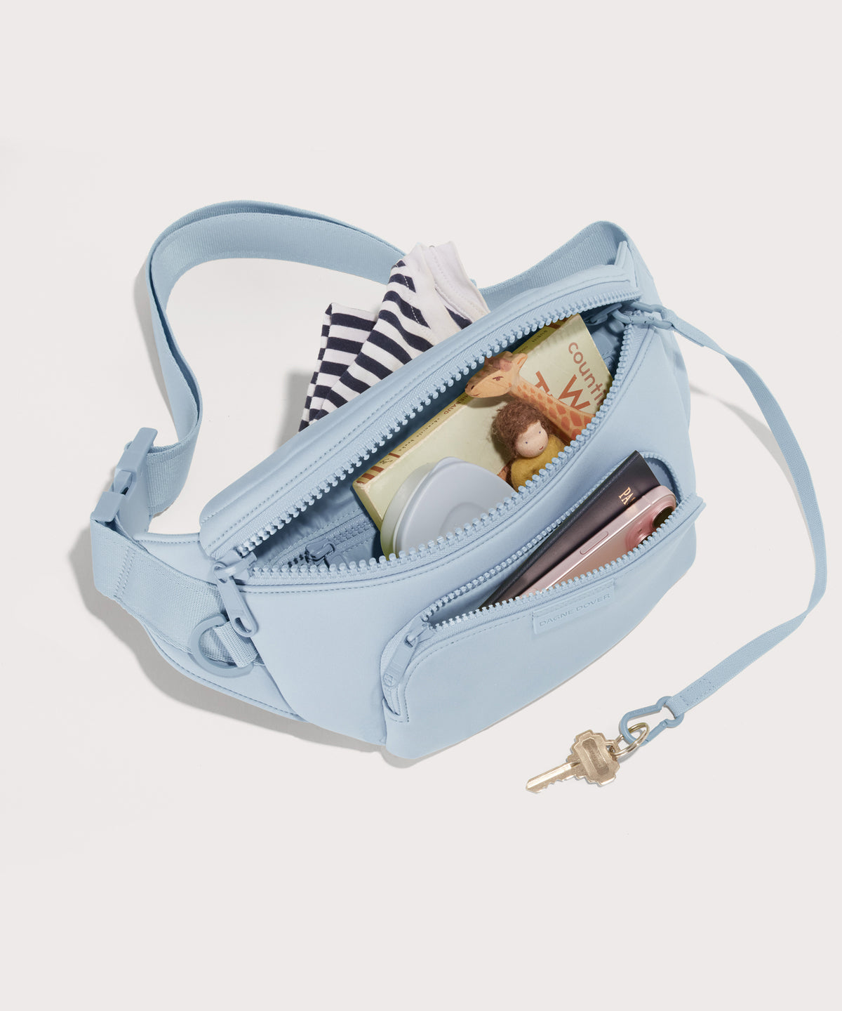 Dagne Dover jax large Fanny Pack in an airy, lighter sky blue unzipped, exposing the interior pockets.