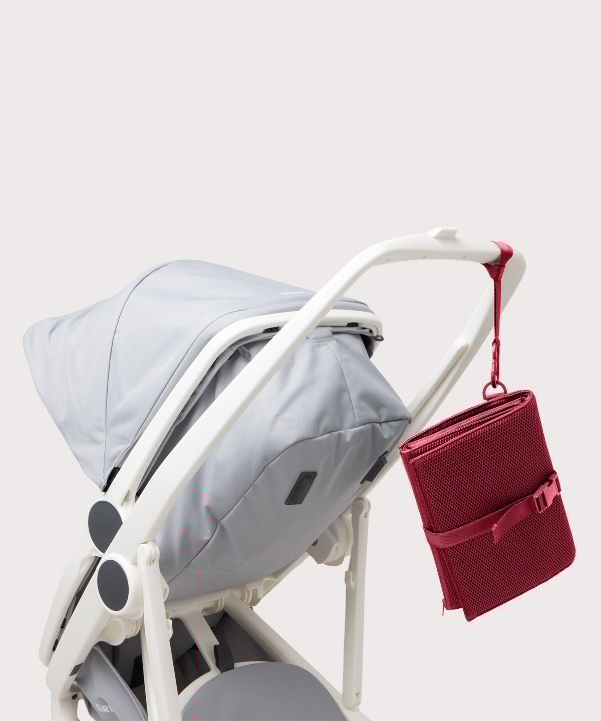 Dagne Dover Joey Changing Kit in spice strapped to the handle of a stroller.
