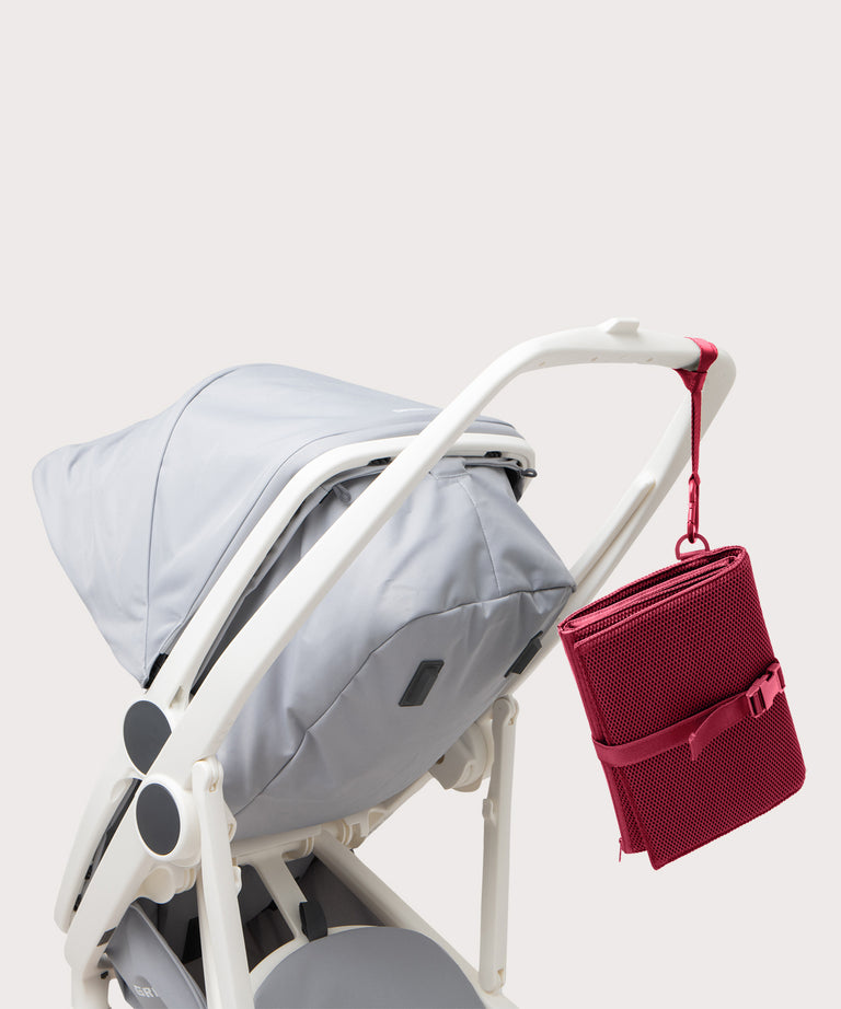 Dagne Dover Joey Changing Kit in spice strapped to the handle of a stroller.
