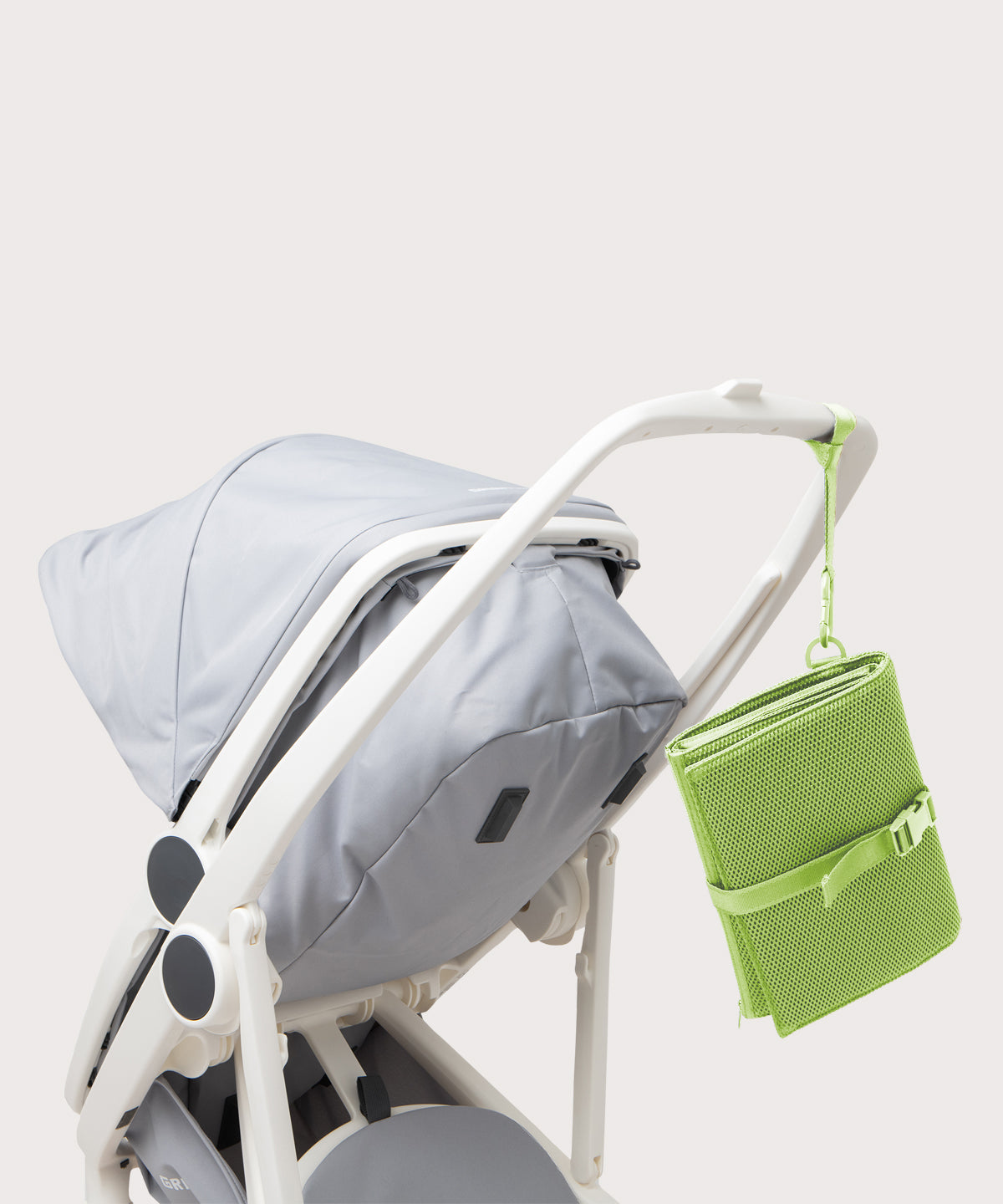 Dagne Dover Joey Changing Kit in matcha strapped to the handle of a stroller.
