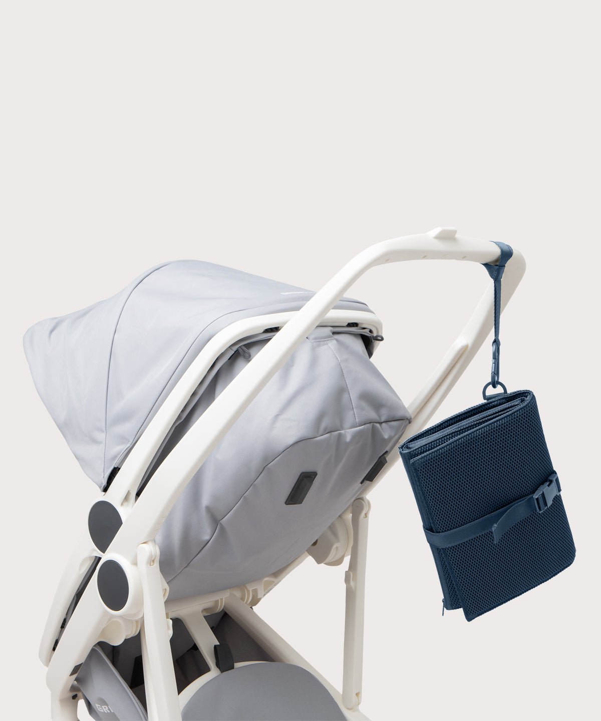 Dagne Dover Joey Changing Kit in moonlight strapped to the handle of a stroller.
