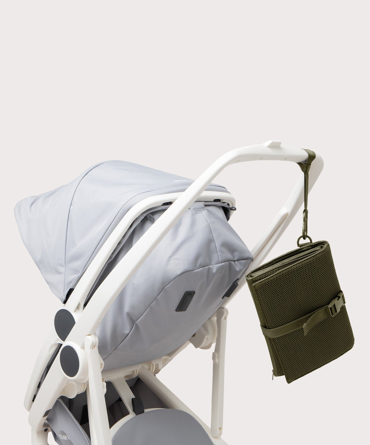 Dagne Dover Joey Changing Kit in dark moss strapped to the handle of a stroller.
