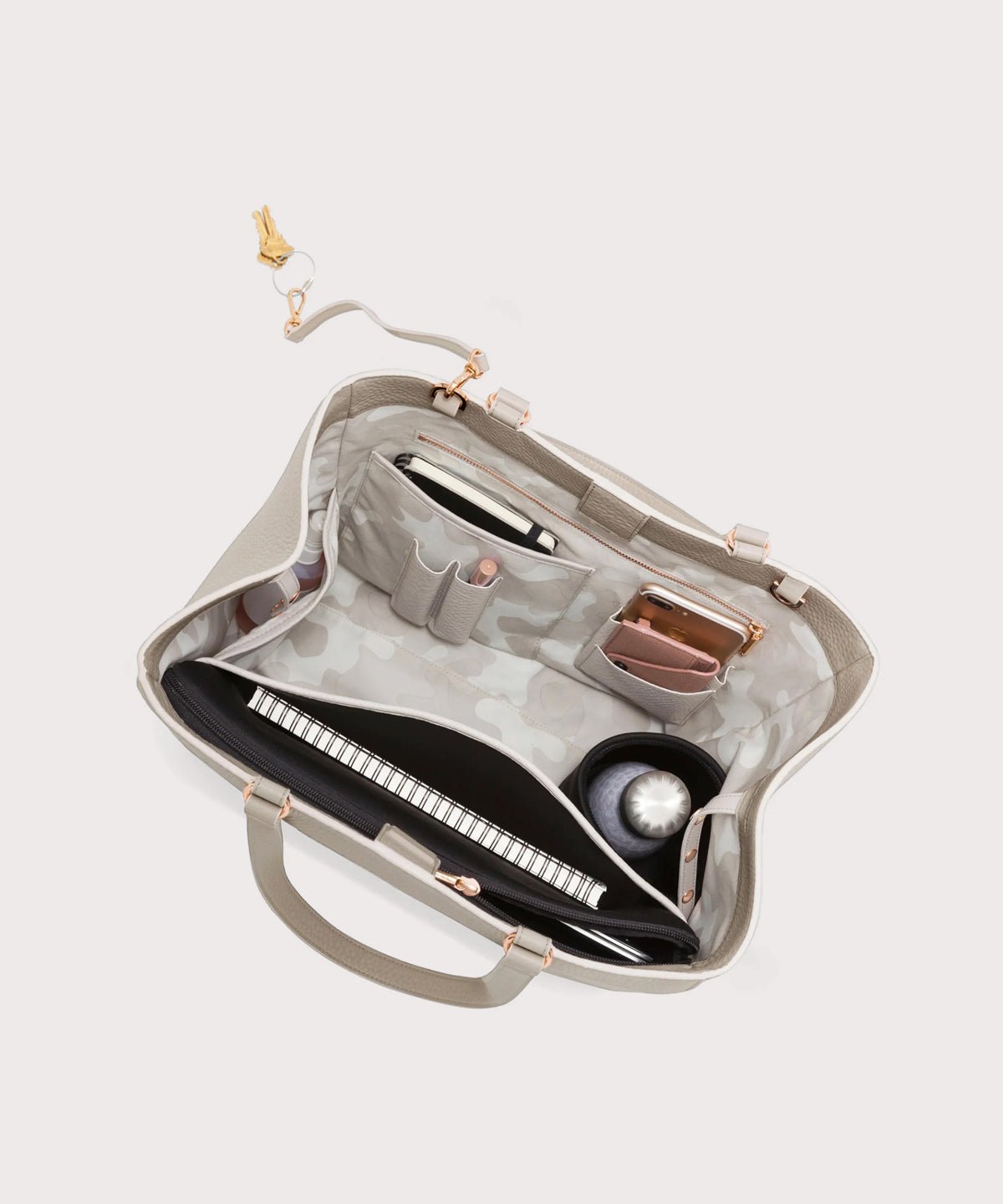 Dagne Dover large Allyn Tote in grey with objects inside the interior pockets.
